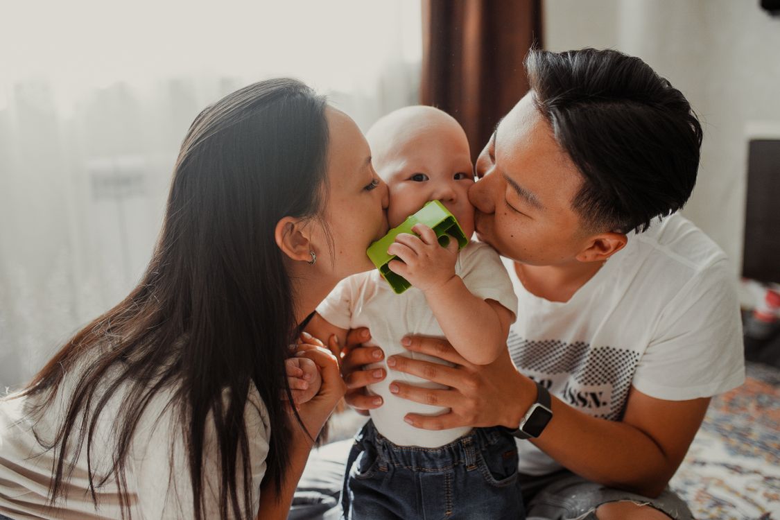 Parents affectionately kissing their baby, a close family moment