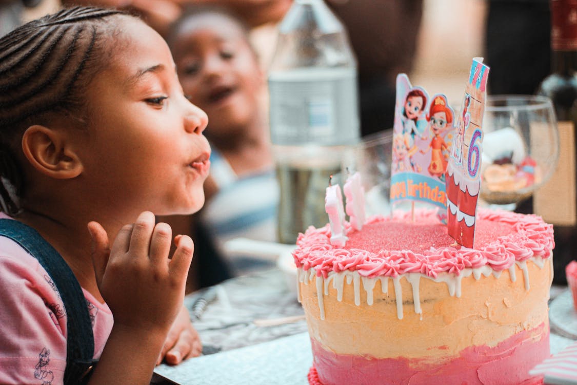 Child blowing out candles on a birthday cake