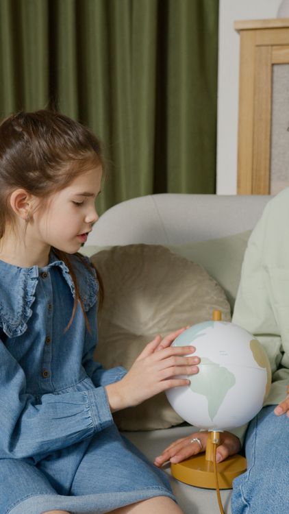 A girl looking at a globe on the sofa at home