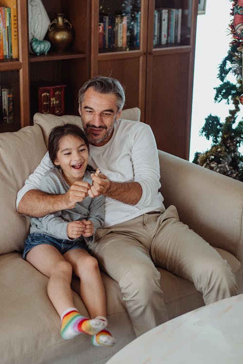 Father and daughter playing together on the sofa