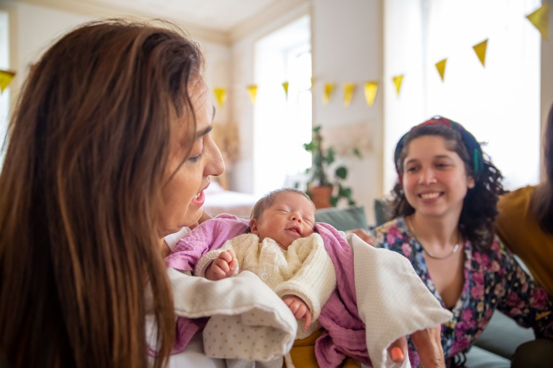 A mother holding her newborn baby, wrapped in a soft blanket