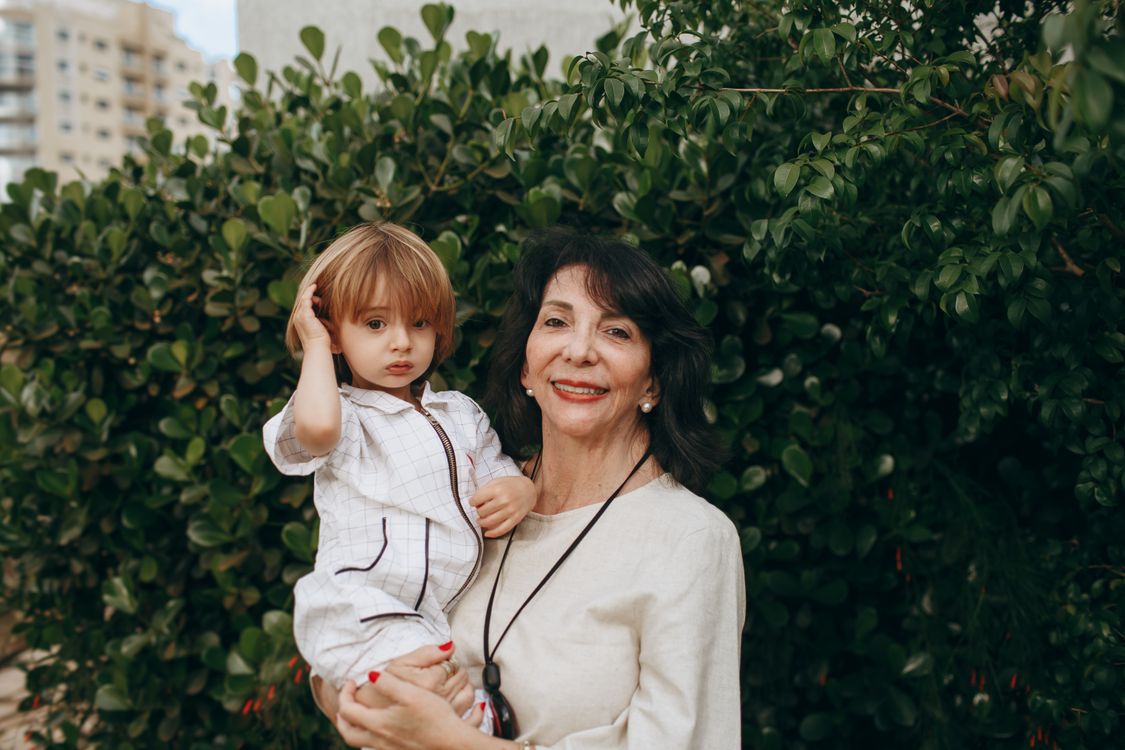 A grandmother outdoors with her grandchild in the sunlight