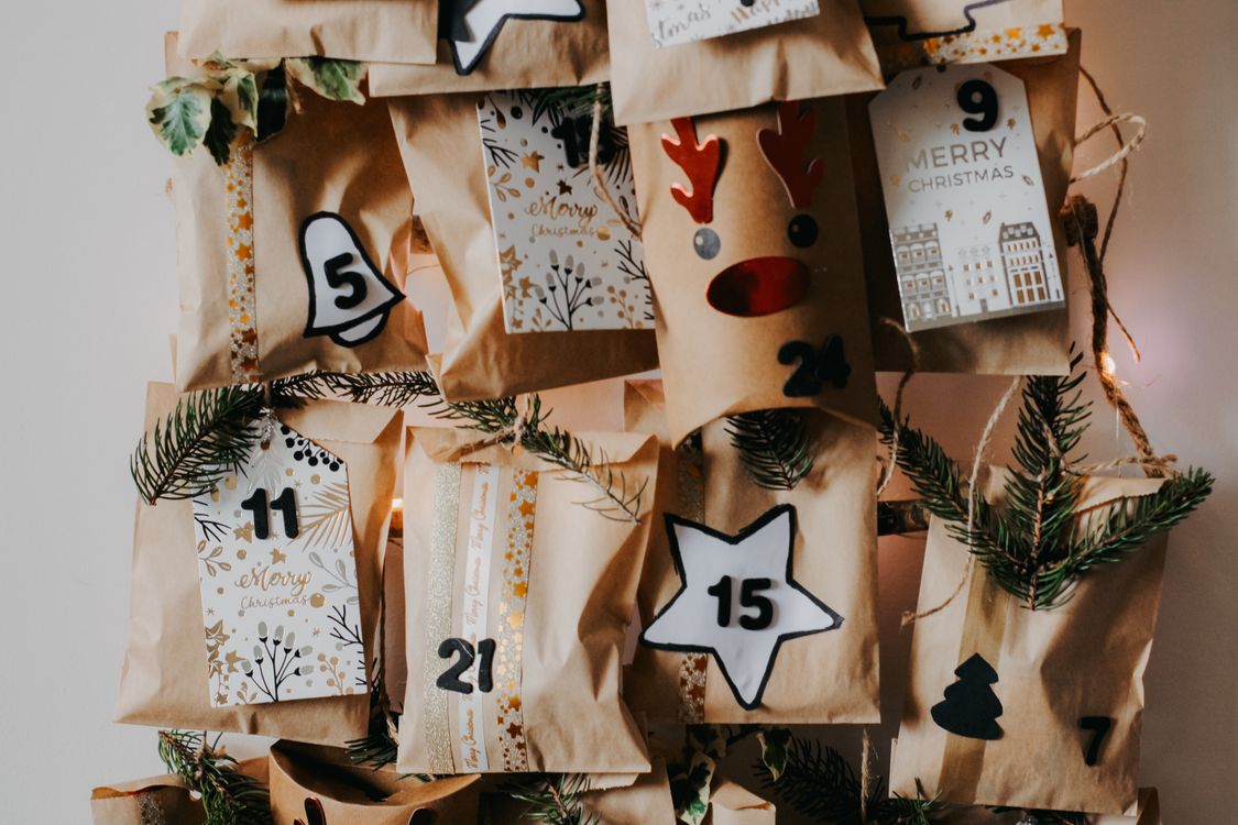 A handmade advent calendar of numbered paper bags with pine sprigs