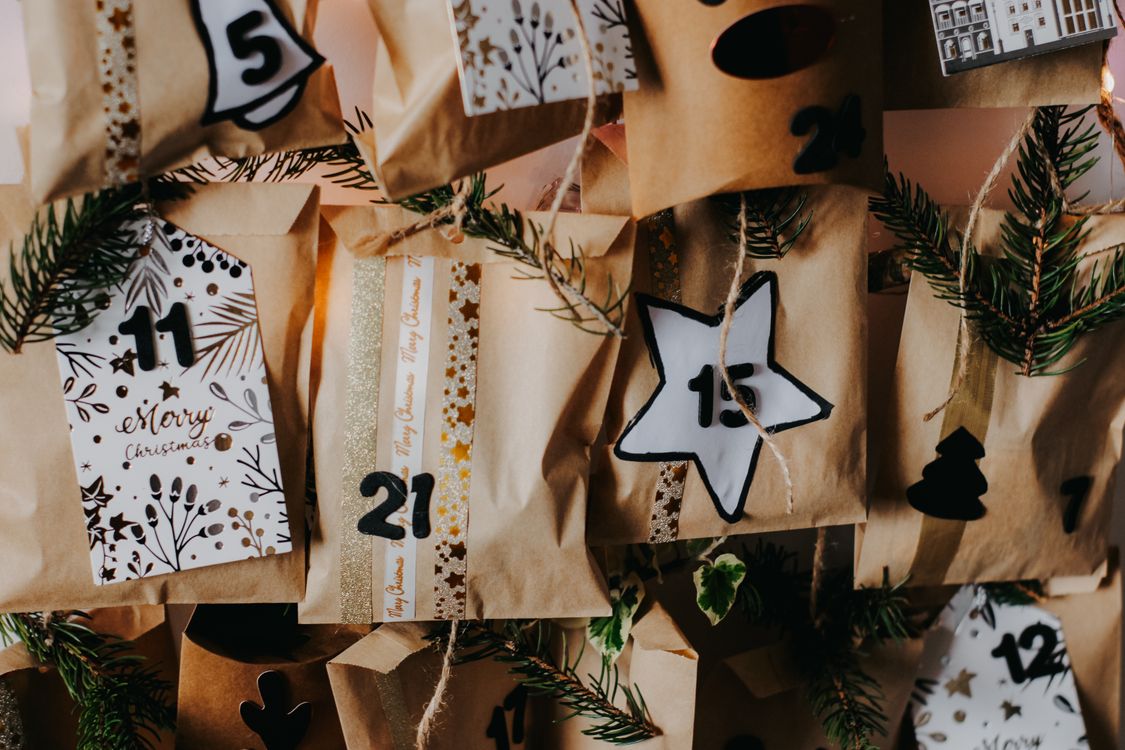 Close-up of a handmade advent calendar with numbered bags and pine sprigs