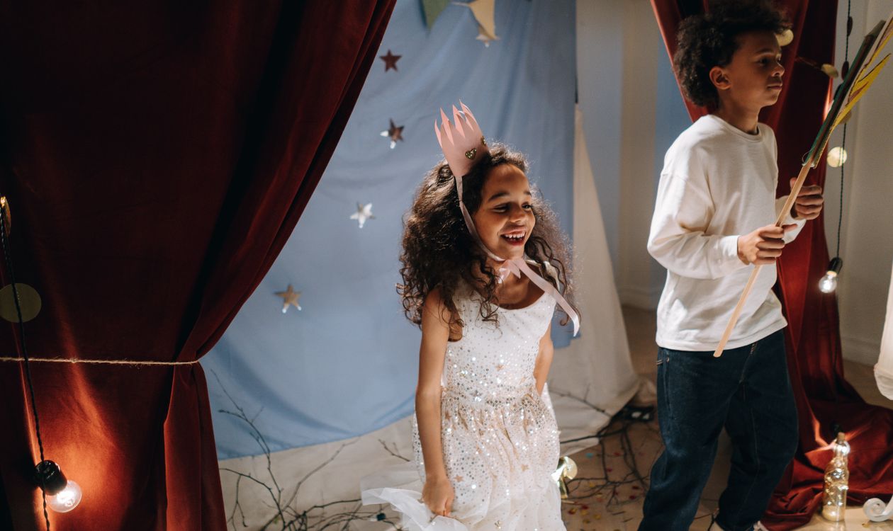 Two children in costume acting out a scene in front of a curtain