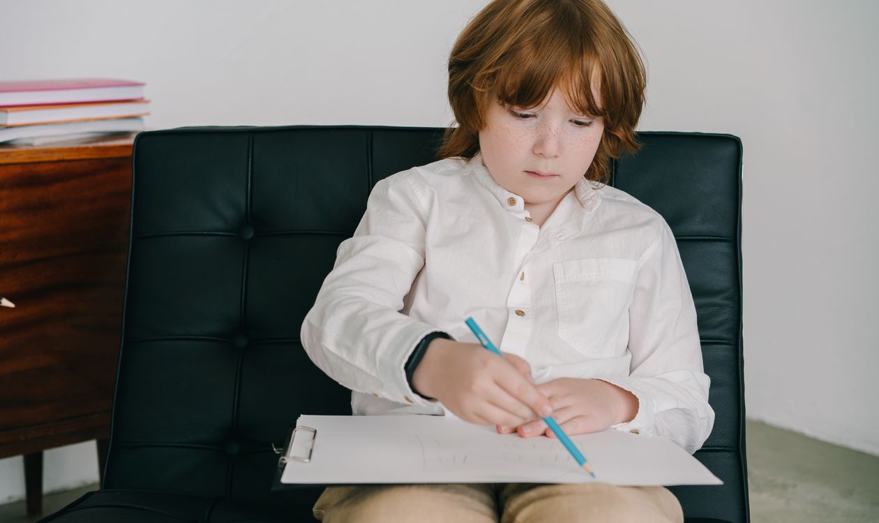 A boy drawing on his own, deep in concentration