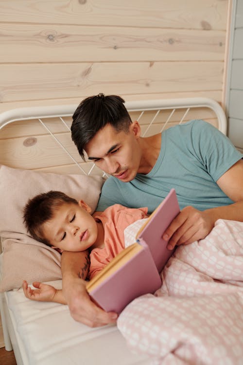 Father reading a personalised book to his child in bed
