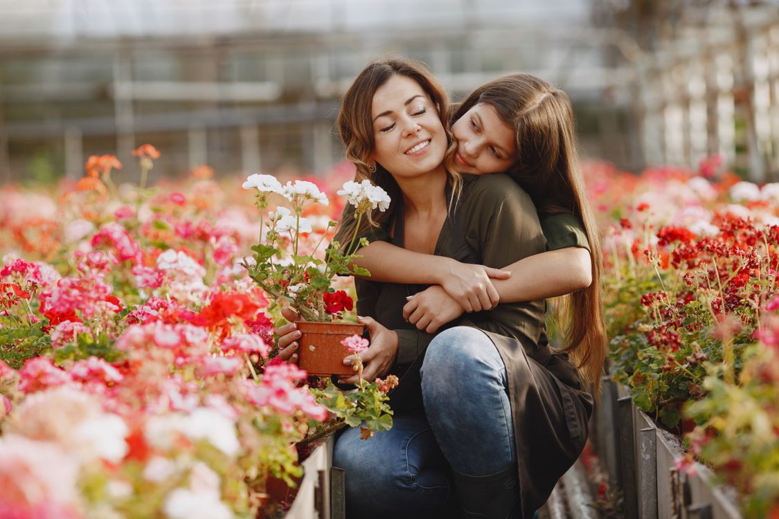 A mother and daughter hugging in a flower garden