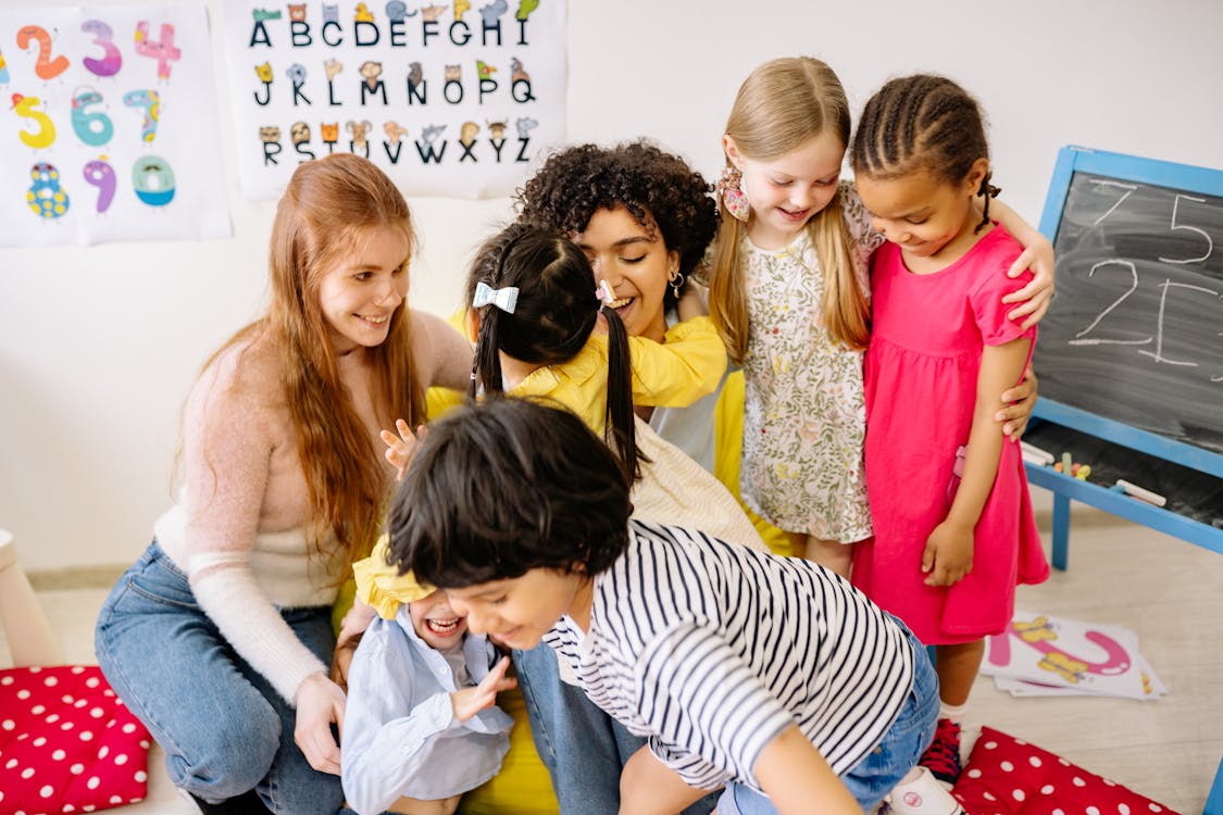 Children in a classroom with an alphabet poster on the wall