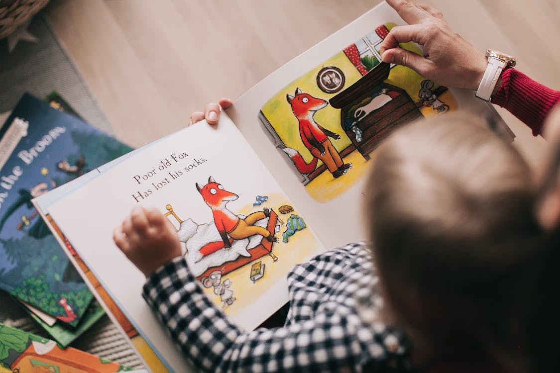 Child looking at a picture book with an originally drawn fox character