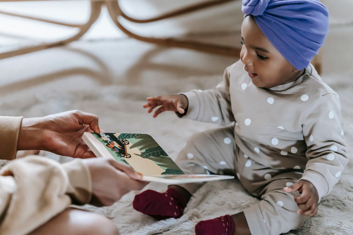 A parent showing a colourful picture book to a toddler