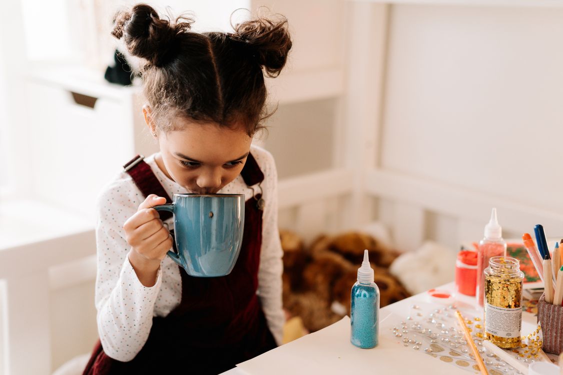 A girl with a mug among craft supplies