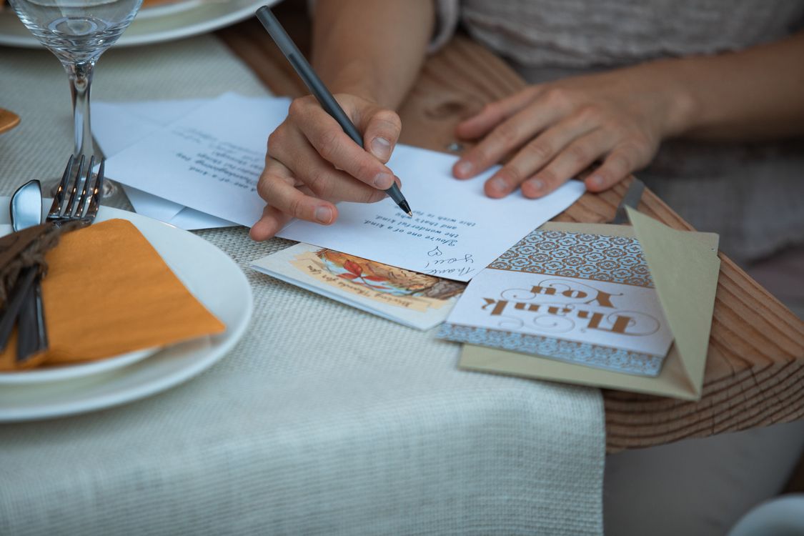 Someone writing a thank-you note at a table set for Thanksgiving