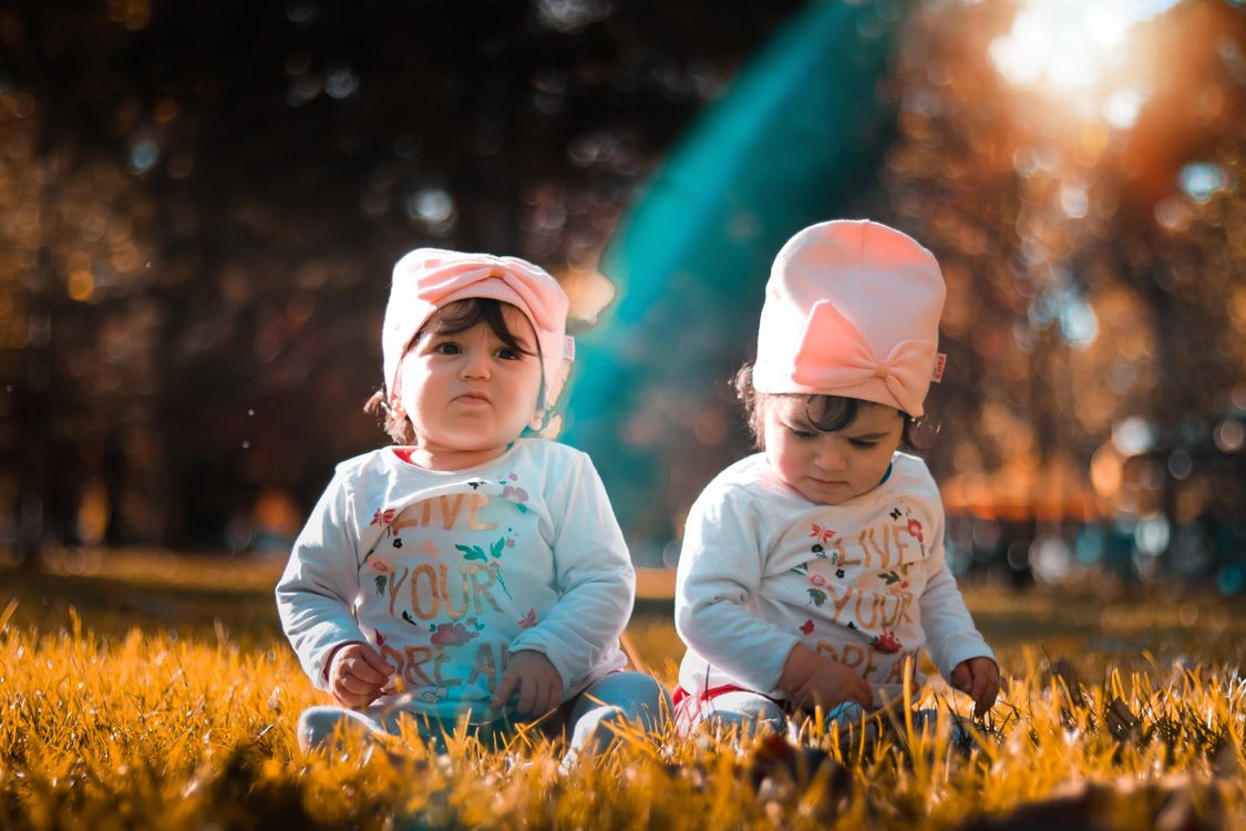 Twins in matching outfits sitting on the grass