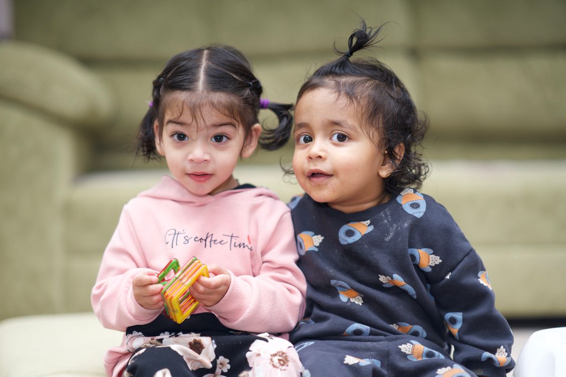 Twins playing together with building blocks on the floor