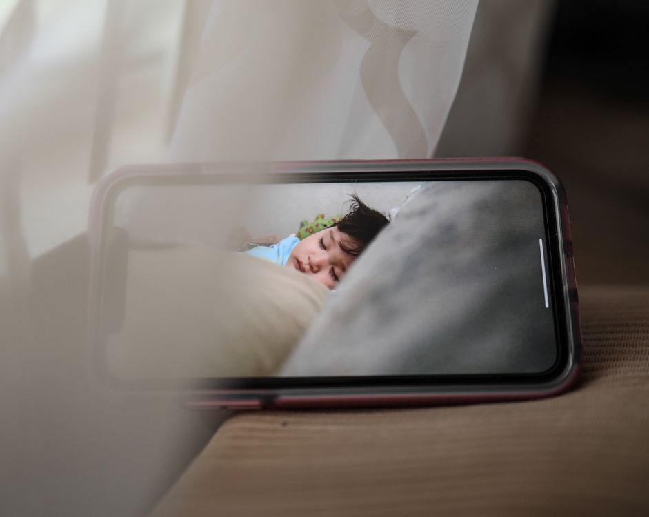 Smartphone screen showing a sleeping child via a baby monitor camera
