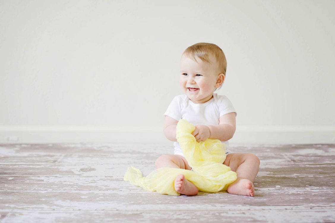 A laughing baby on a yellow blanket