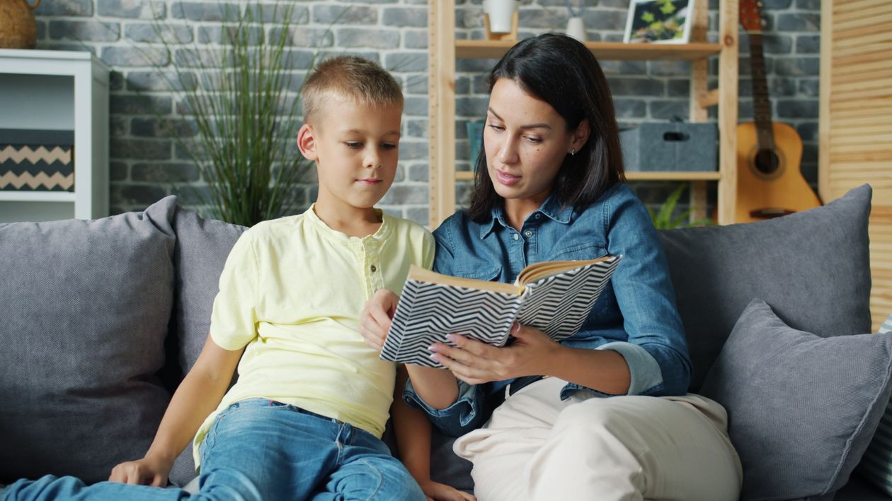 Mother and child reading a book together on a sofa